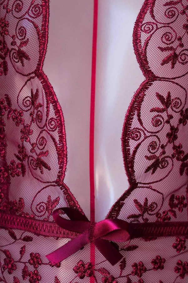 Details de l'ornements de dentelles sur la poitrine d'un manequin qui expose le body tailleur en dentelles bordeaux avec sont magnifique noeuds papillons en satin.